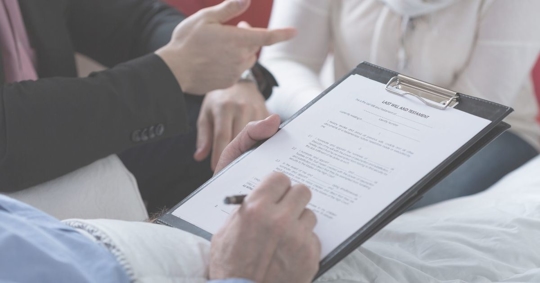 bedridden person signing a document